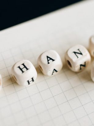 Close-up of letter dice spelling 'change' on a grid notepad, symbolizing transformation.