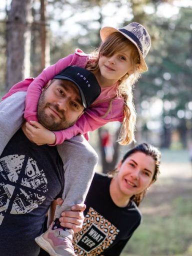 A joyful family enjoying a playful day in a sunlit forest park, capturing the essence of togetherness.