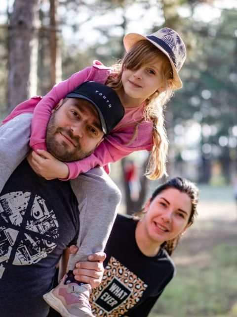 A joyful family enjoying a playful day in a sunlit forest park, capturing the essence of togetherness.