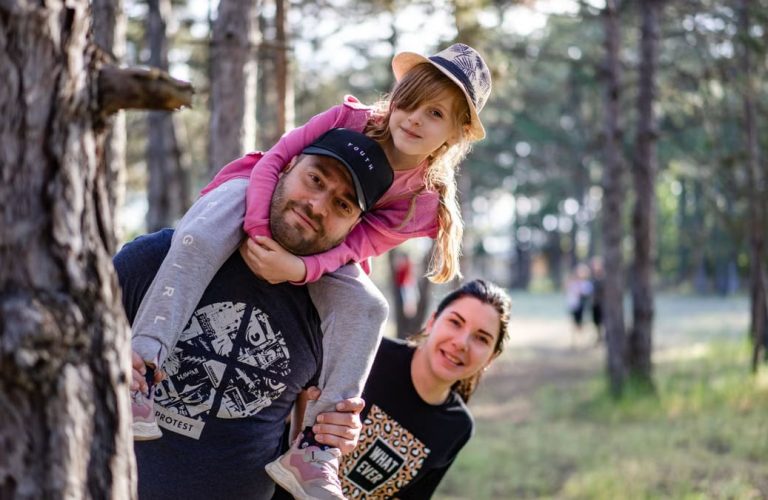 A joyful family enjoying a playful day in a sunlit forest park, capturing the essence of togetherness.